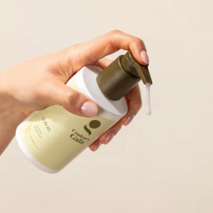 Le Baume Coton démêlant après-shampoing certifié bio Couleurs Gaïa 200 ml est tenu par une main qui actionne la pompe en montrant la texture de ce soin après-shampoing