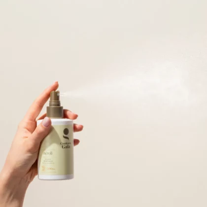Néroli, la brume démêlante sans rinçage et thermo-protectrice certifiée bio de 200ml est tenu par une main qui actionne la pompe montrant ainsi le produit qui se disperse.