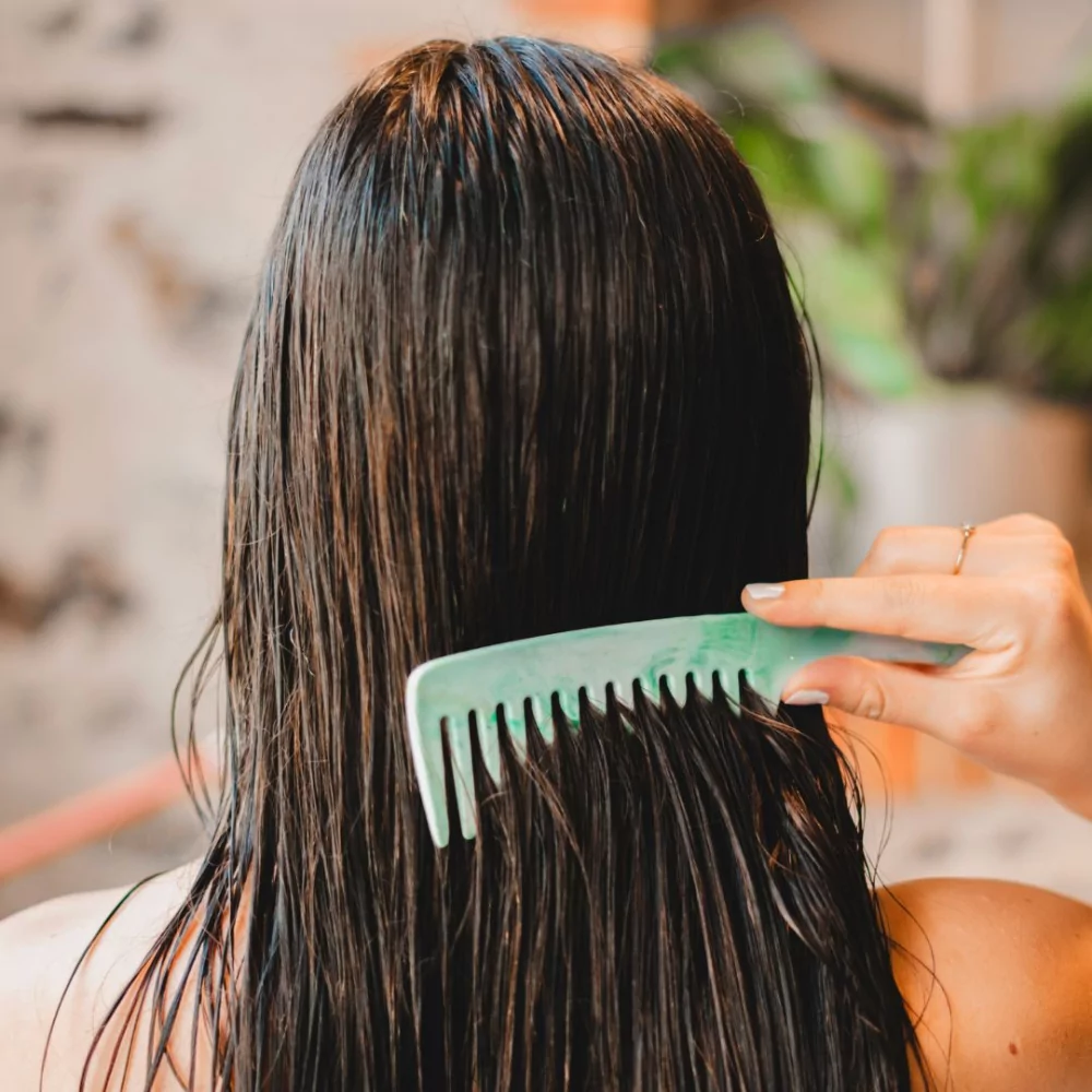 Le visuel montre une main en train de se démêler les cheveux mouillés avec le peigne 100% recyclé Couleurs Gaïa