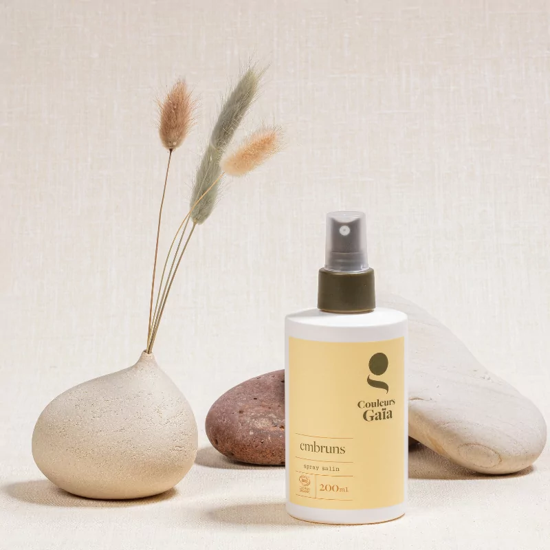 Embruns, le spray salin certifié bio de 200ml est fermé, posé devant des galets naturels, ambiance minérale, naturelle.